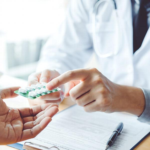 a doctor handing a patient prescribed pills